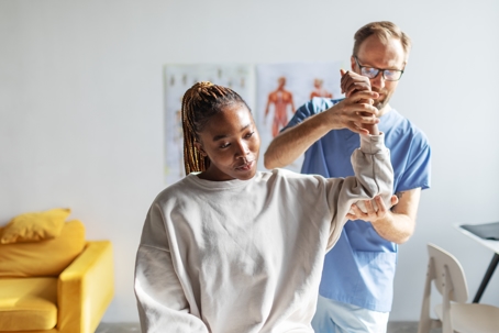 physical therapist helping a woman with her shoulders