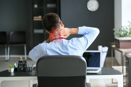 Man sitting at work desk with neck pain